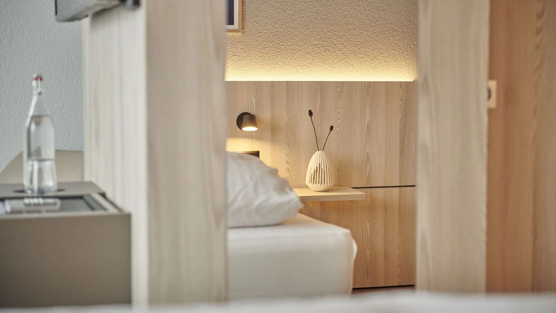 View through doorway to bed and bedside table in modern hotel room