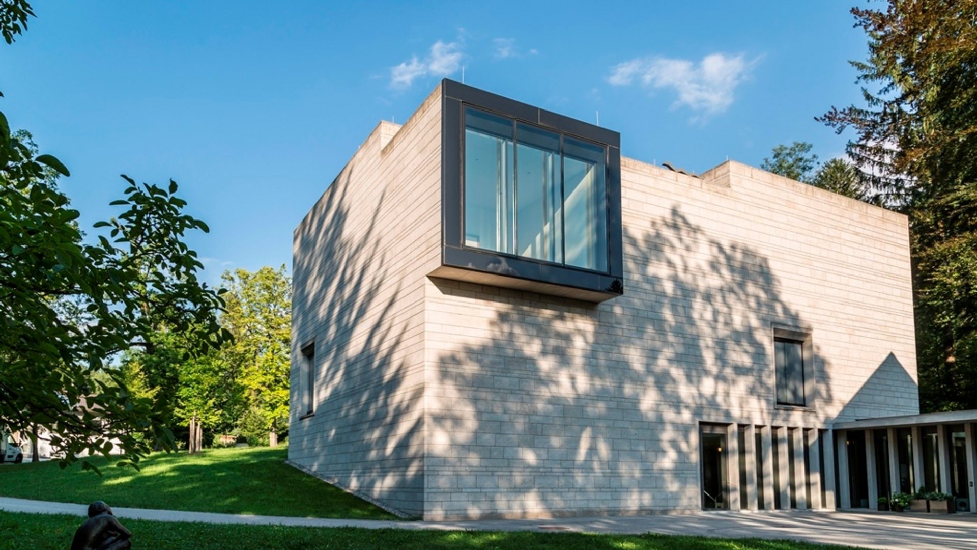Modern cubic concrete building in a green park on a sunny day