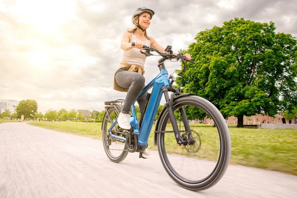 Übertreffe deine Erwartungen © Ralf Bohle GmbH Frau fährt Fahrrad auf einem Weg im Park an einem sonnigen Tag