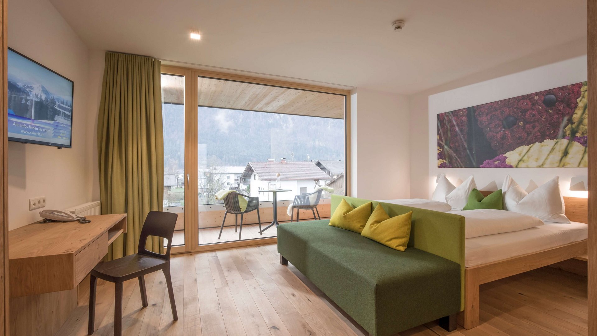 Modern hotel room with balcony, double bed and comfortable sofa