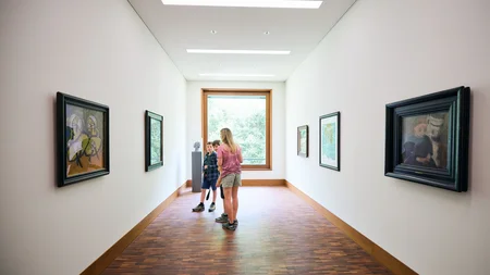 Kinder betrachten Kunstwerke in einem modernen Museumskorridor