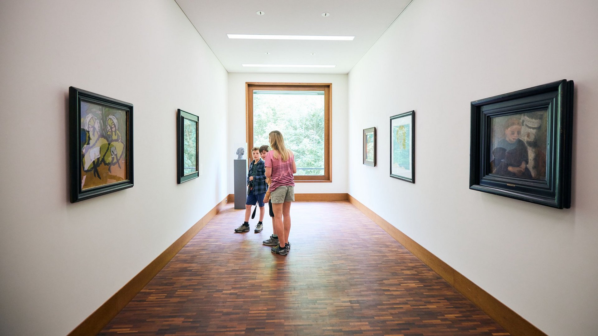 Children viewing artworks in a bright, modern museum hallway