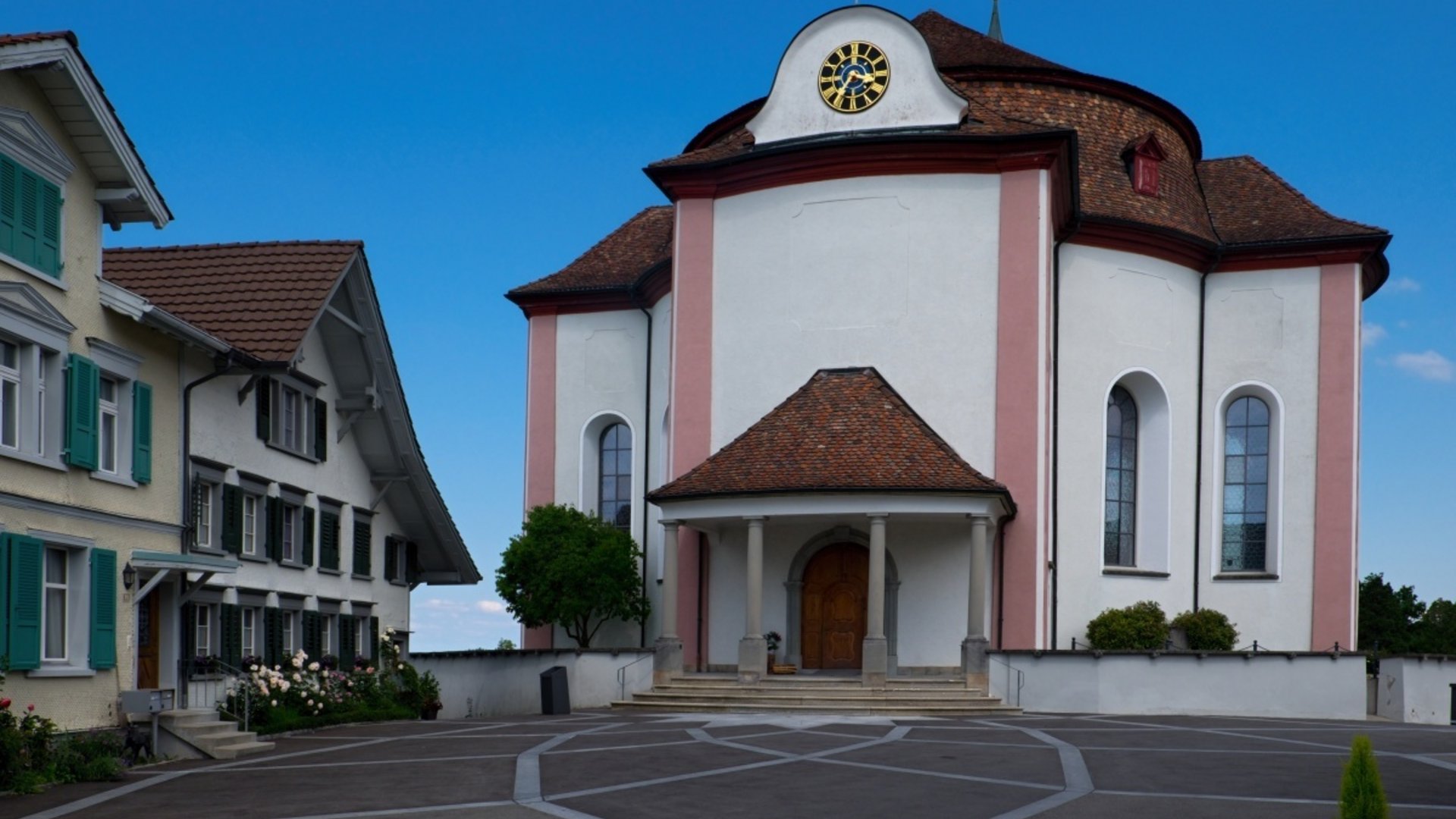 White baroque church building with round roof and clock on the front