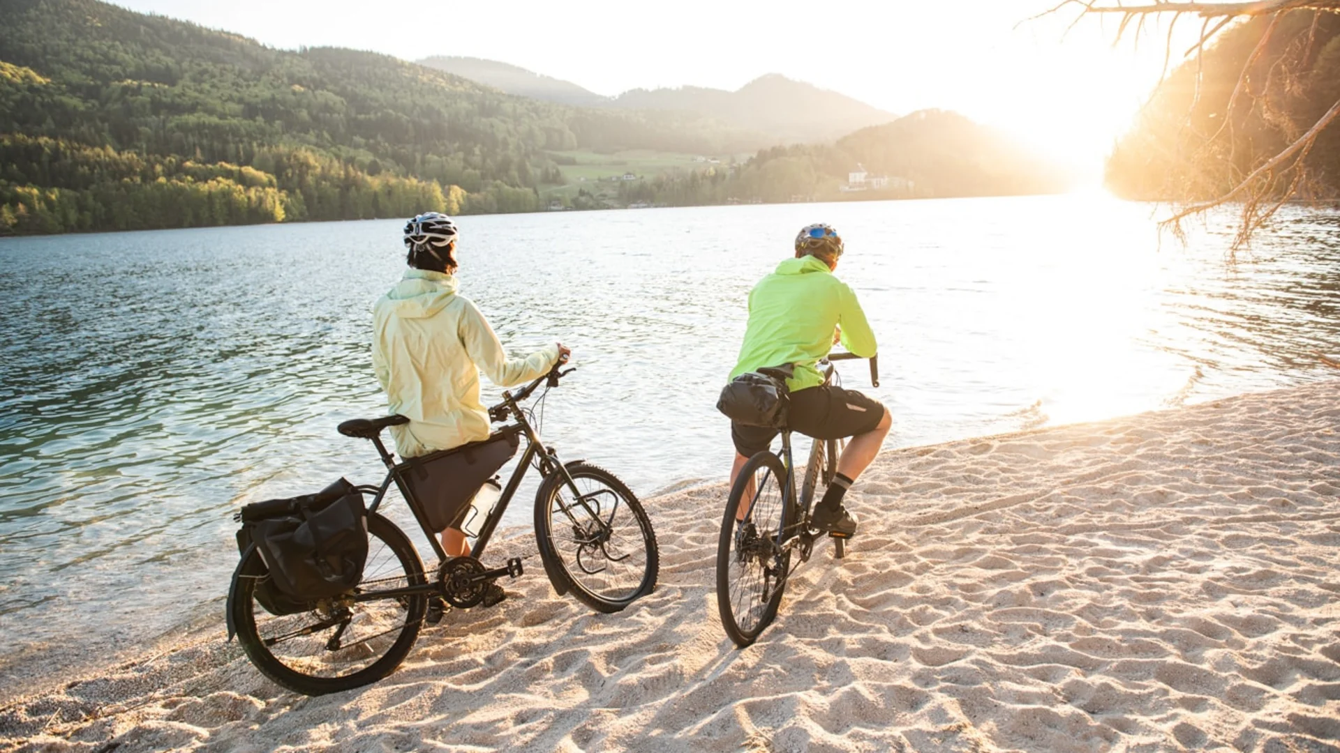 Two cyclists by lakeside at sunset