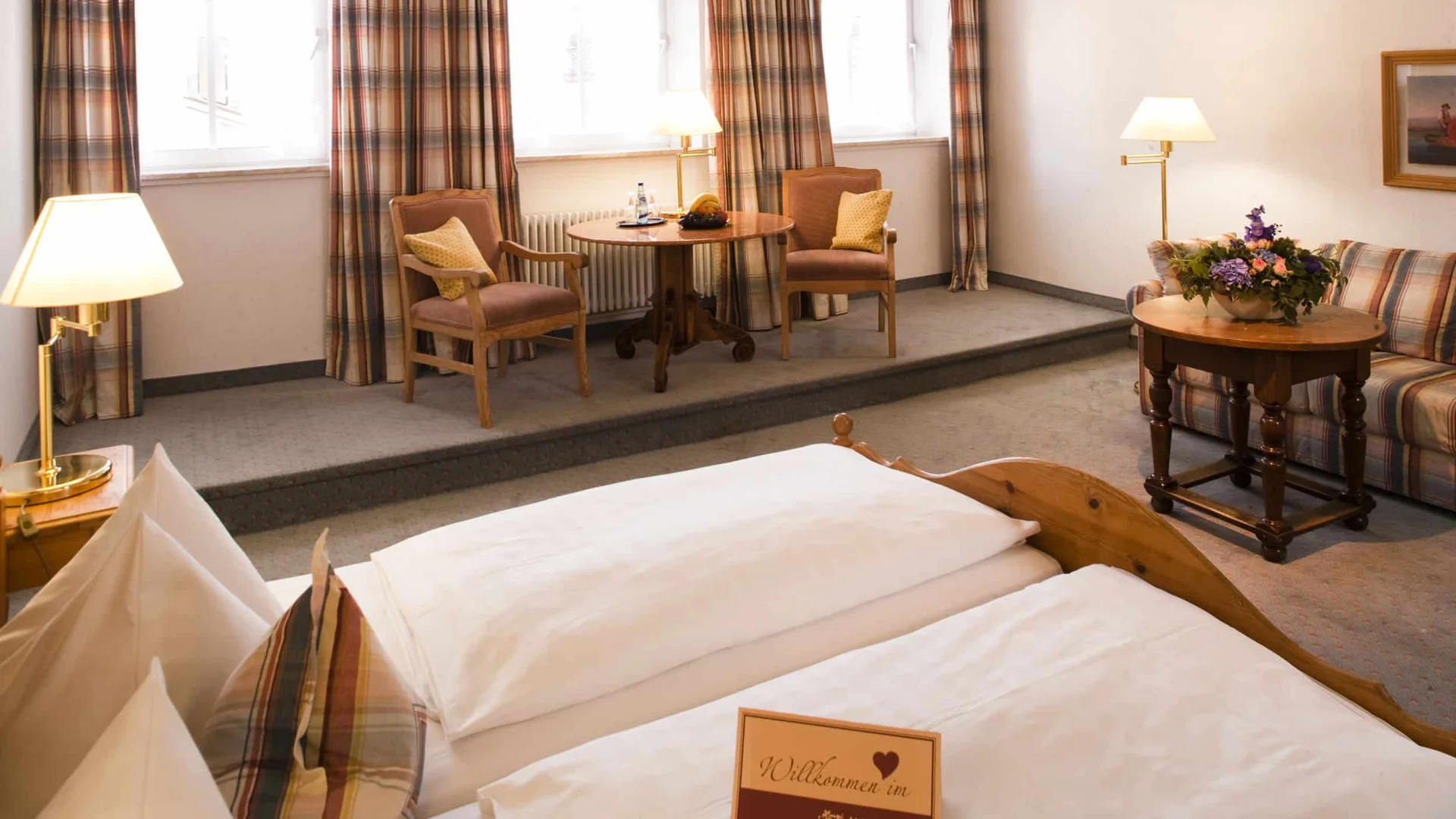 Cozy hotel room with double bed, table, chairs, and sofa