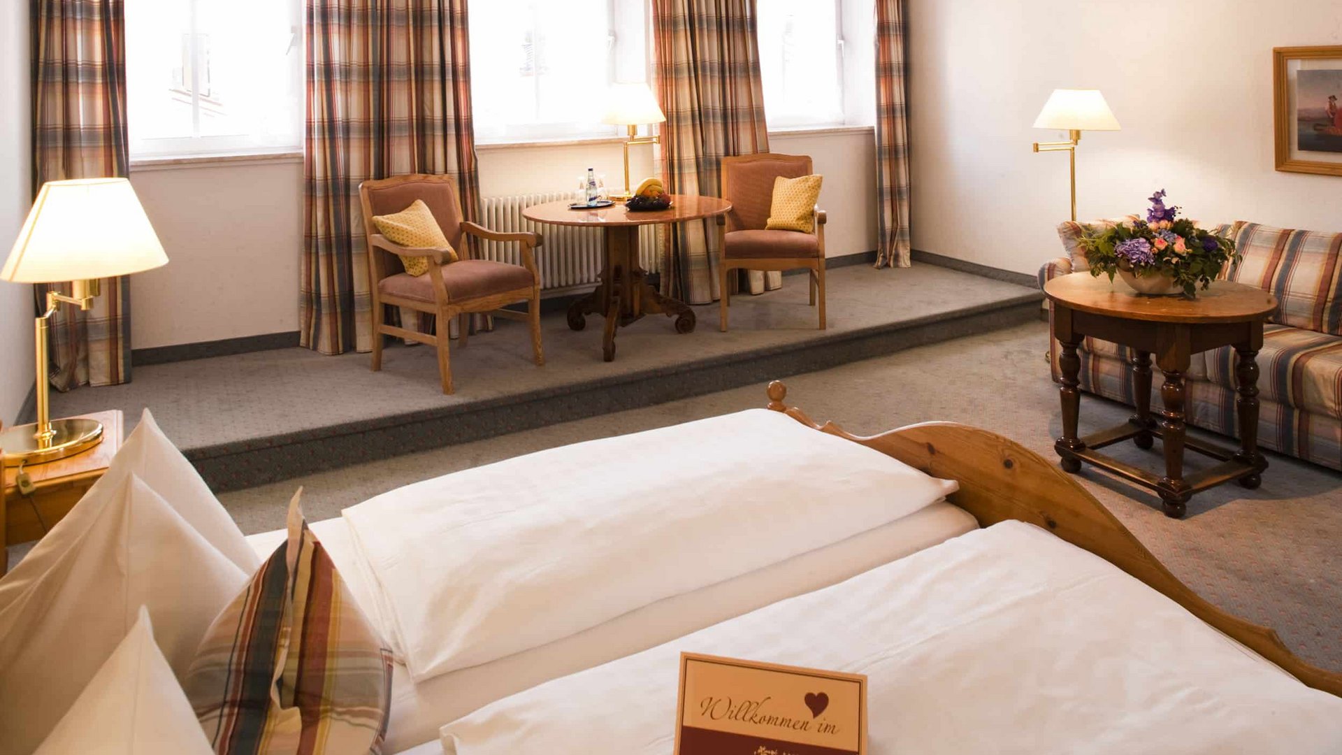 Cozy hotel room with double bed, table, chairs, and sofa