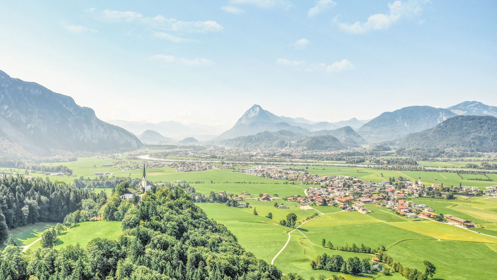 View of green alpine landscape with mountains and a village