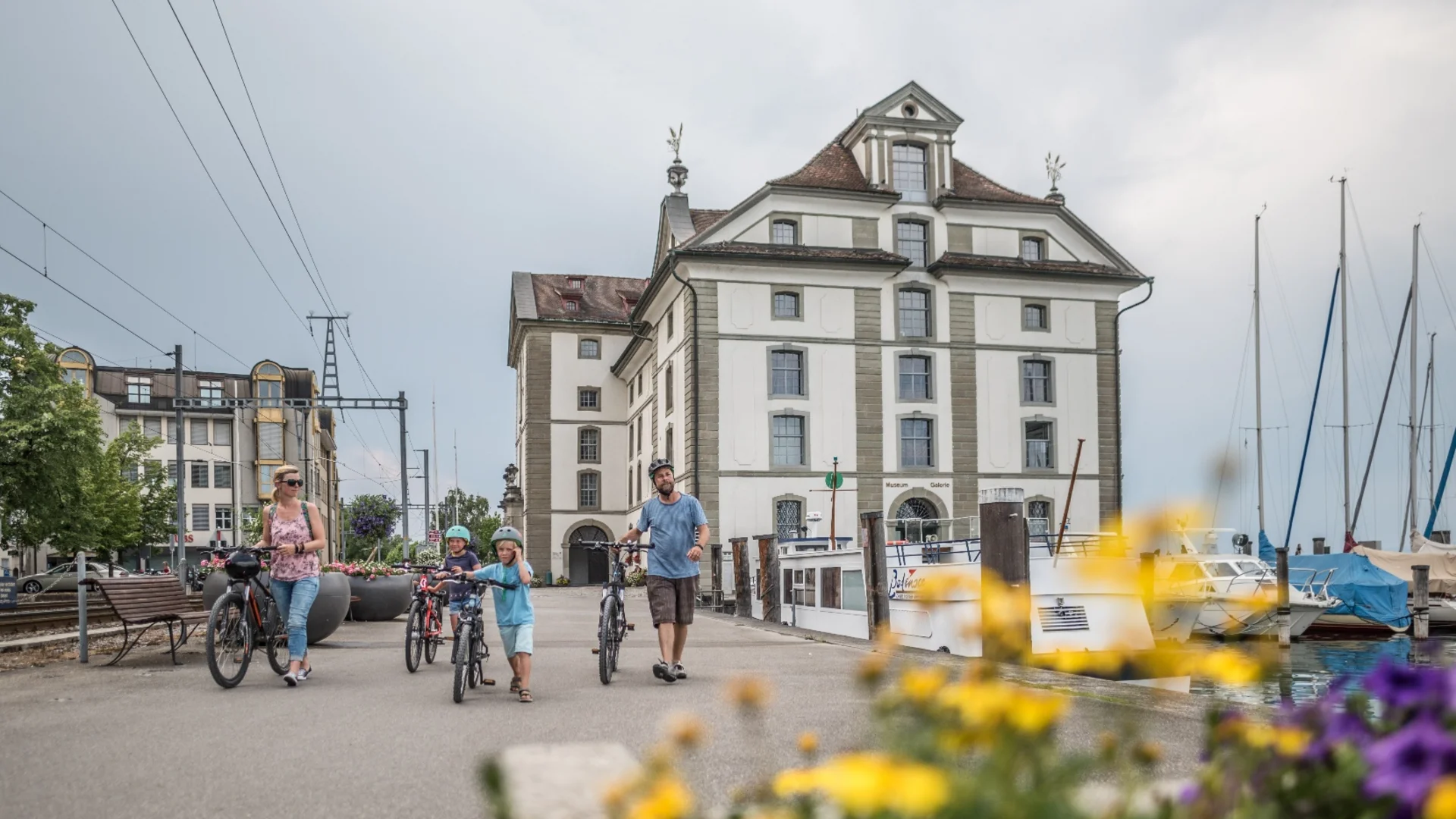 Familie met fietsen bij meerhaven en historisch gebouw