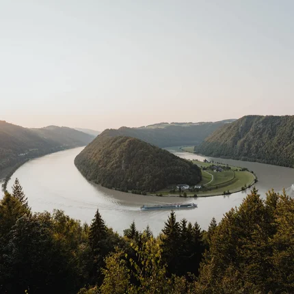 Rivier kronkelt door beboste heuvels bij zonsondergang