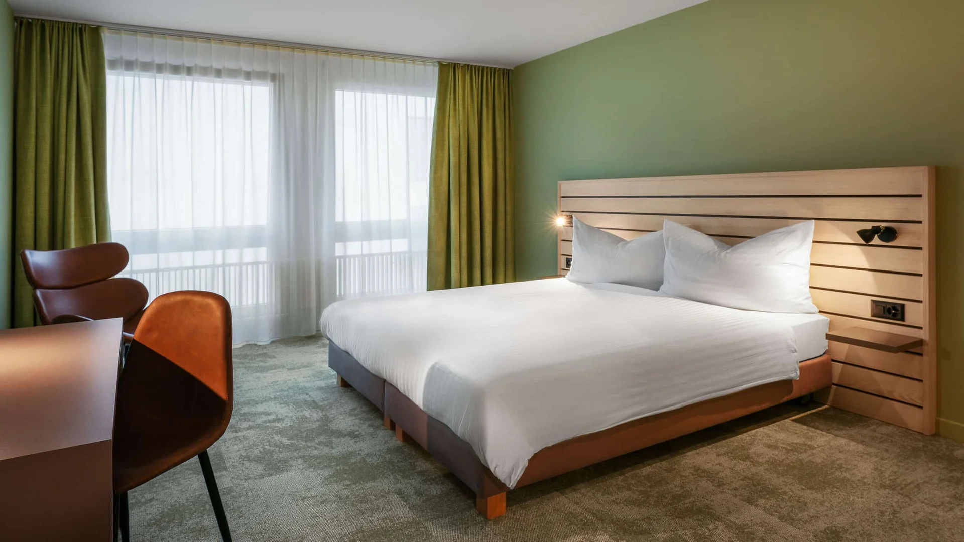 Modern hotelkamer met tweepersoonsbed en groene gordijnen