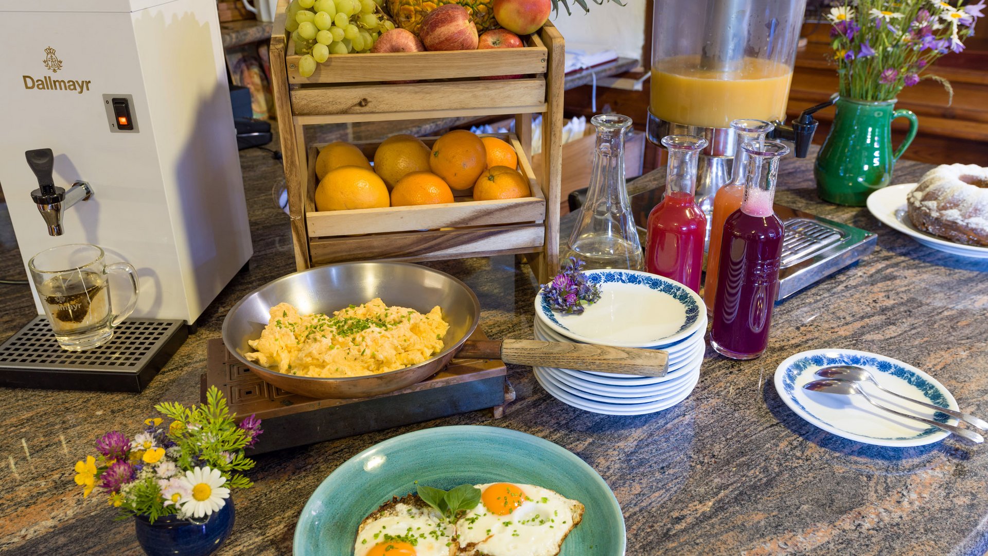 Breakfast spread with eggs, vegetables, juices, and fruit on a table