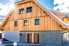 Collective enquiries House with wooden facade and snow-covered roof under sunny sky