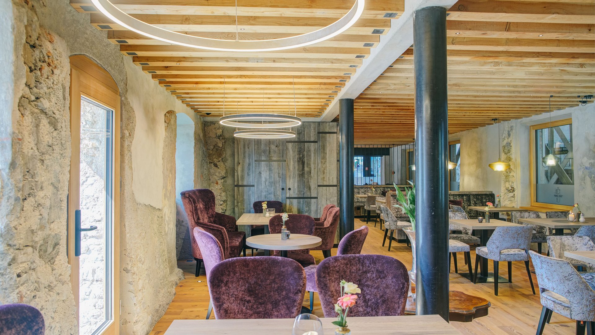 Modern café interior with wooden ceiling, cozy chairs and circular light rings