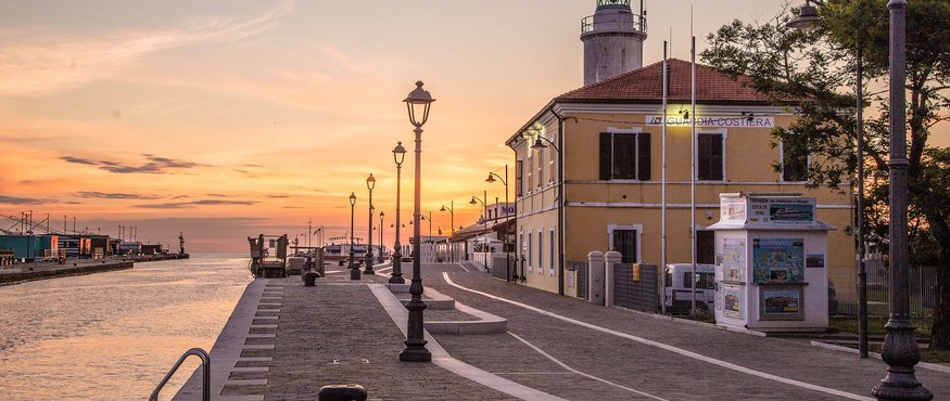 Harbor promenade with lighthouse at sunset