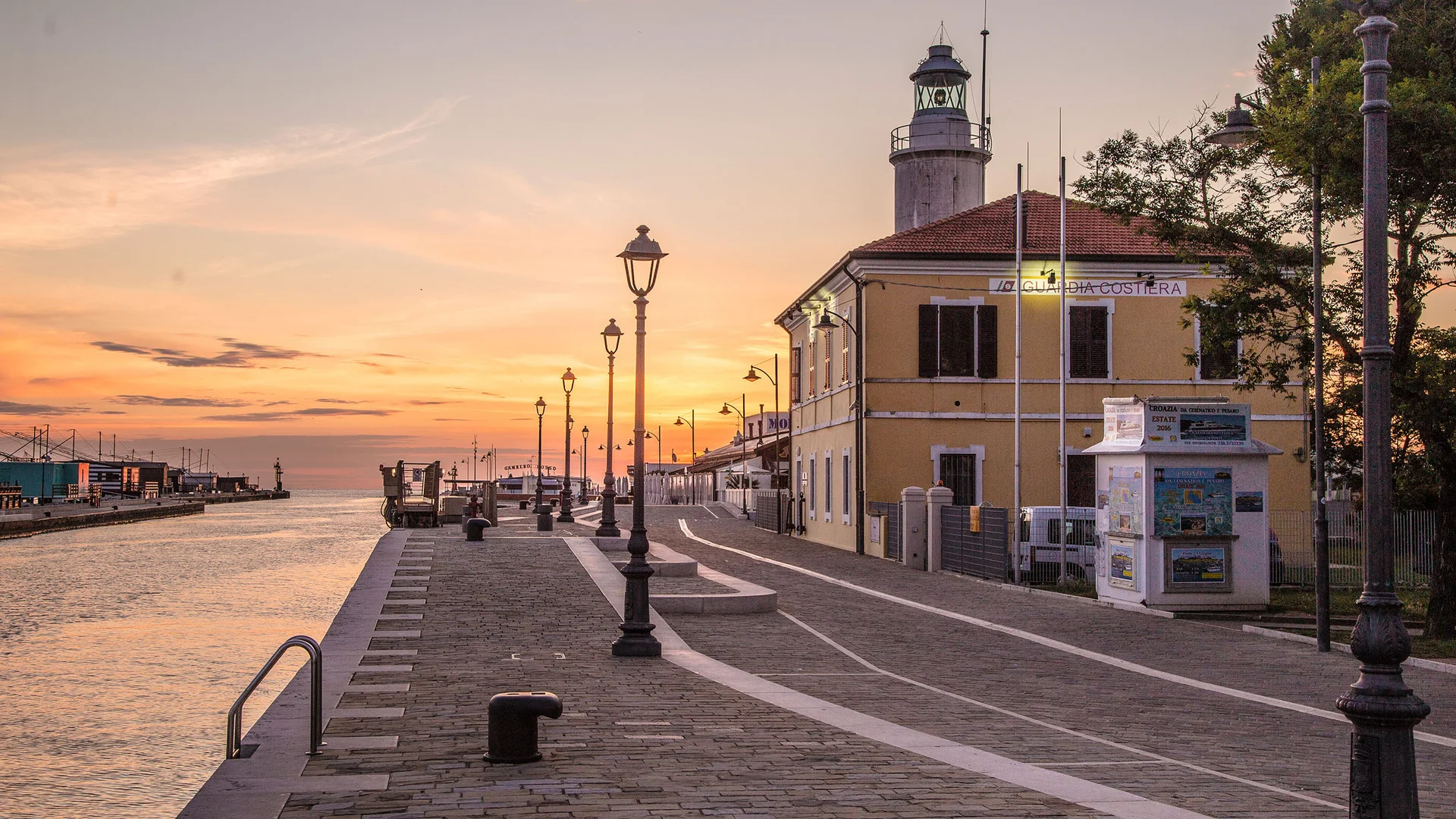 Hafenpromenade mit Leuchtturm bei Sonnenuntergang