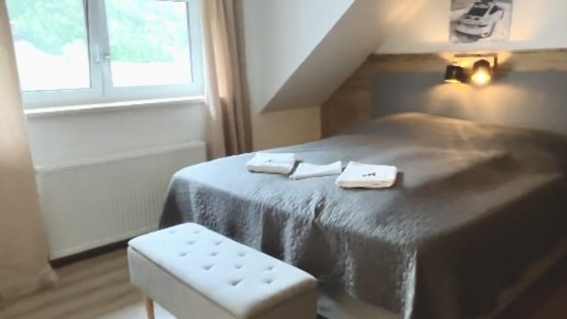 Bedroom with double bed, gray bedspread and window with curtains