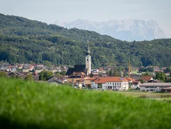 Dorp met kerk voor beboste heuvels en bergen op de achtergrond