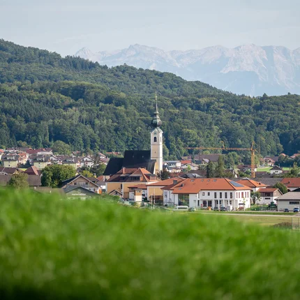 Dorp met kerk voor beboste heuvels en bergen op de achtergrond