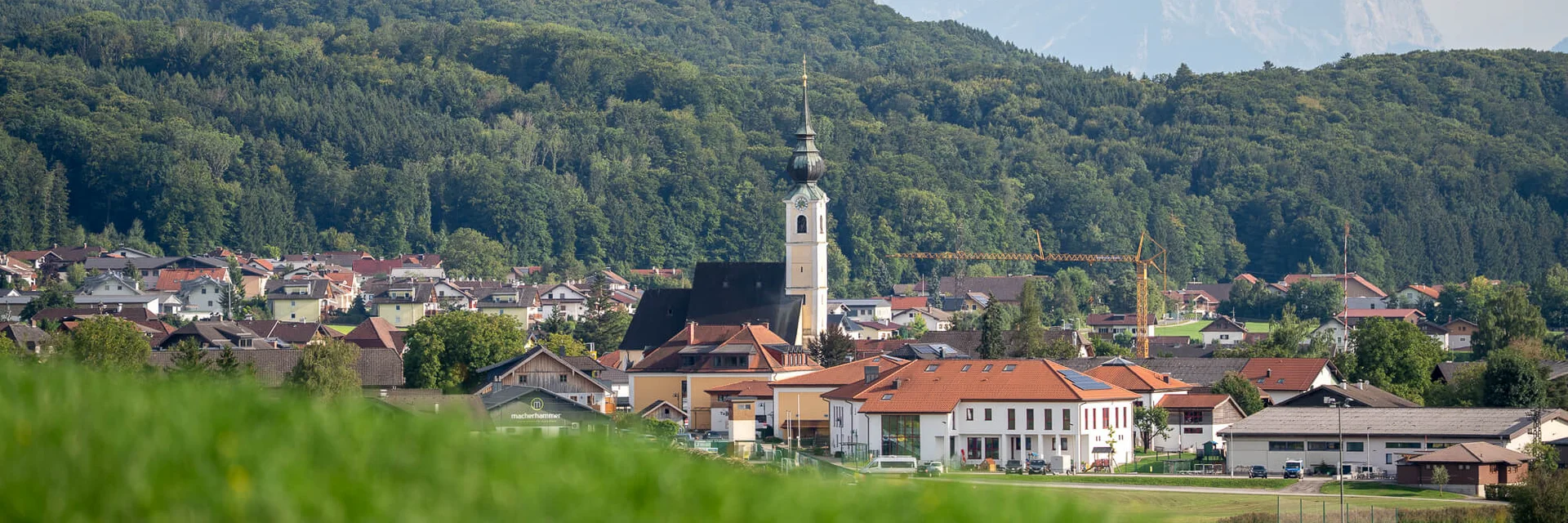 Dorp met kerk voor beboste heuvels en bergen op de achtergrond