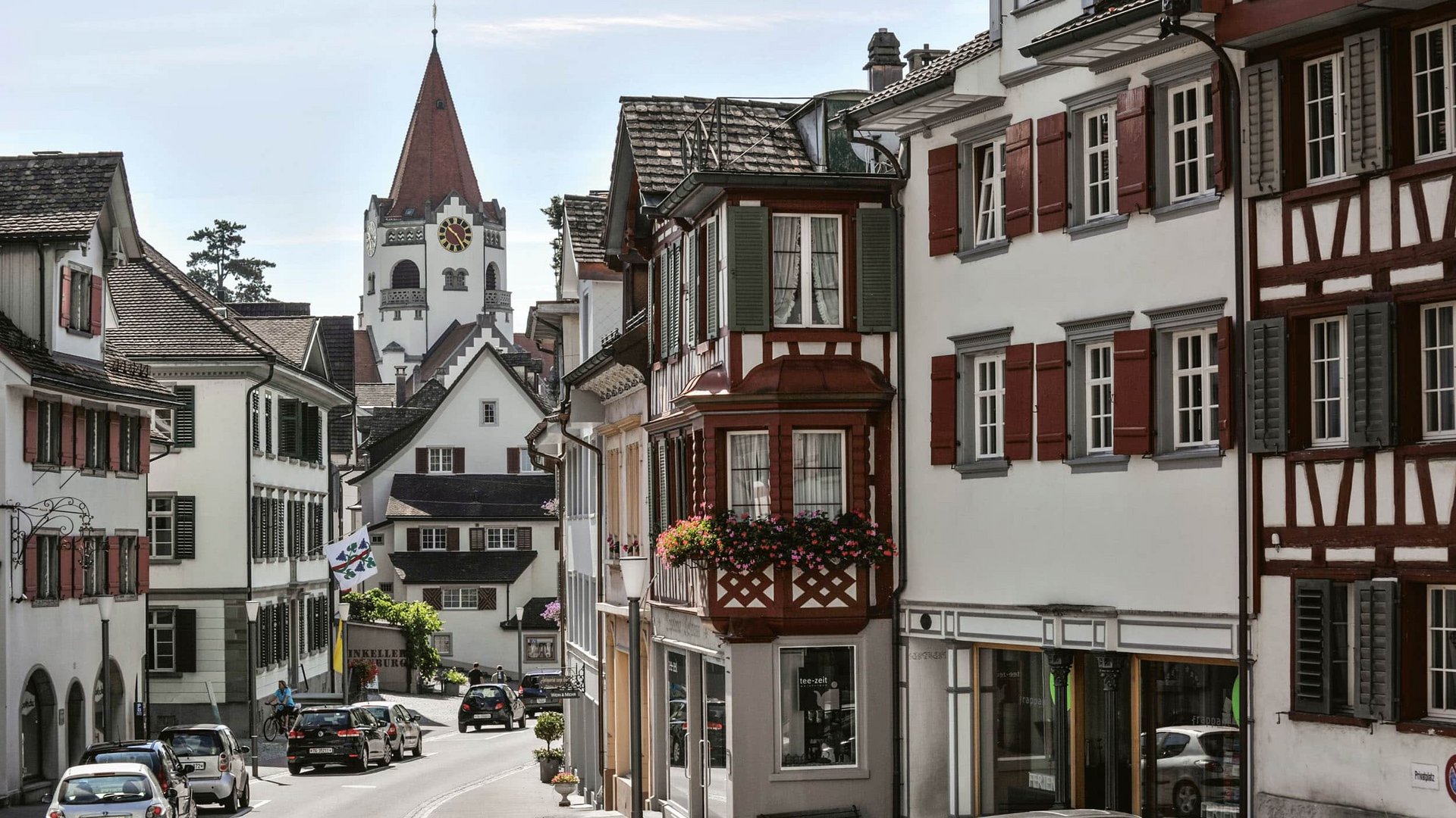 Historic street with timber-framed houses and church tower in background