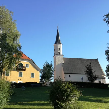 Kerk en geel huis op een heuvel onder een blauwe lucht