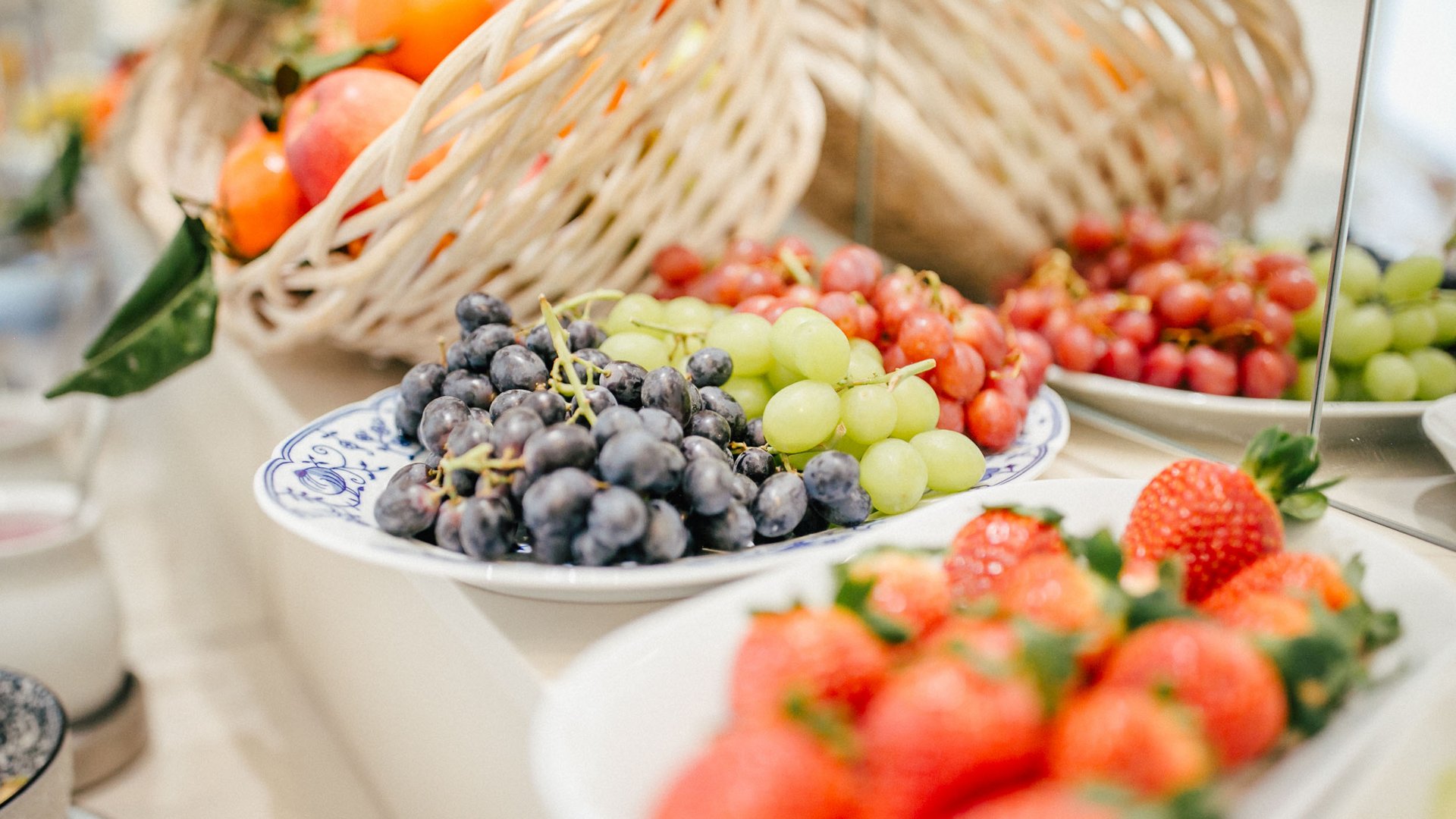 Various fruits on plates, including grapes and strawberries