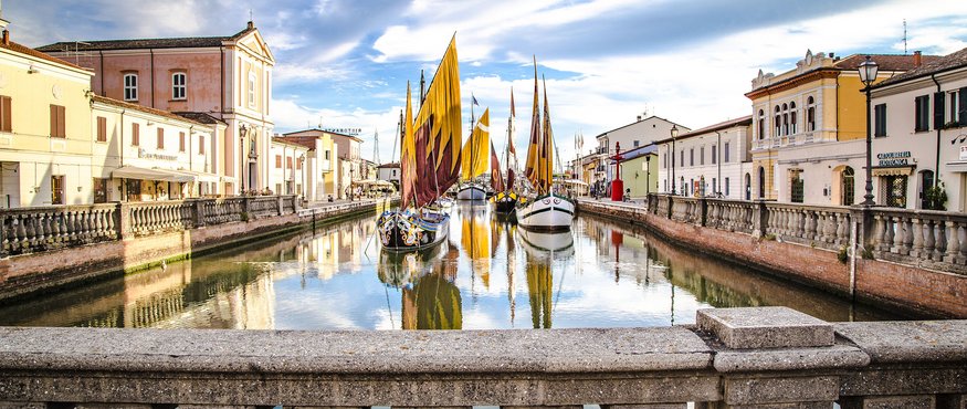 Historic sailboats on a canal in a town with old buildings