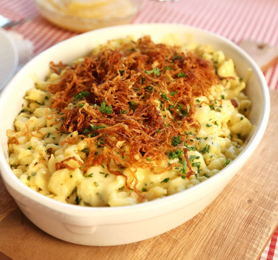 Kaas spaetzle met krokante uitjes en peterselie in een witte ovenschaal