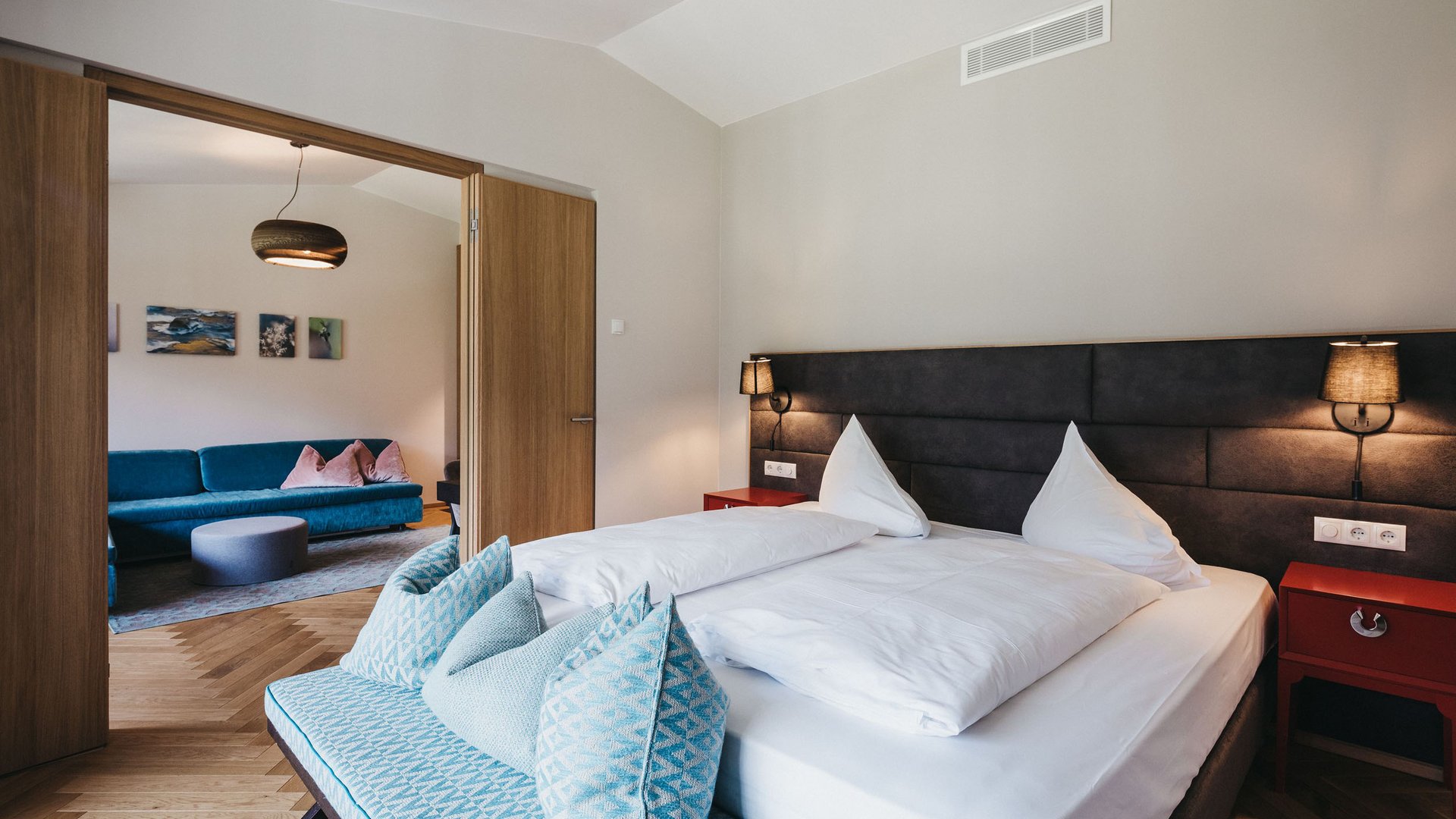 Modern bedroom with open doors to a living room with sofa