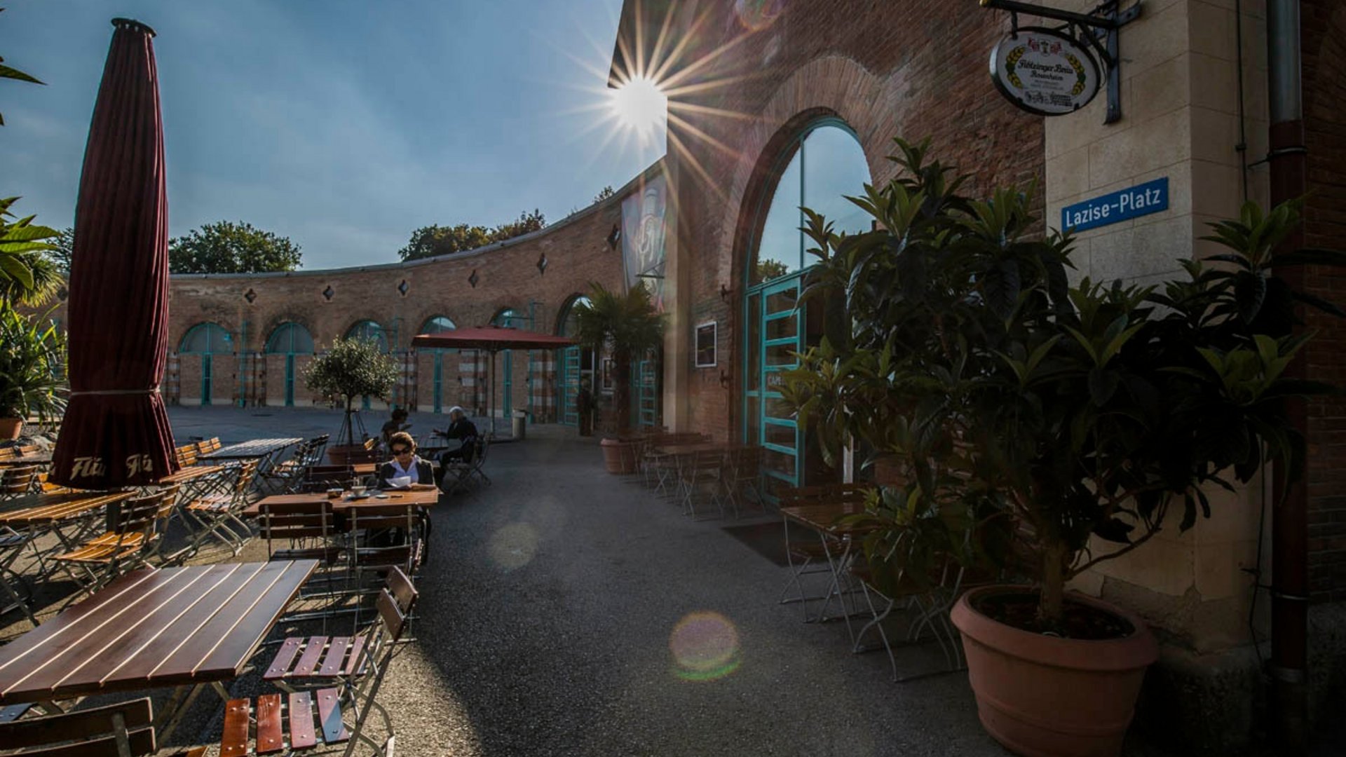 Sunny outdoor café seating with tables, chairs, and plants