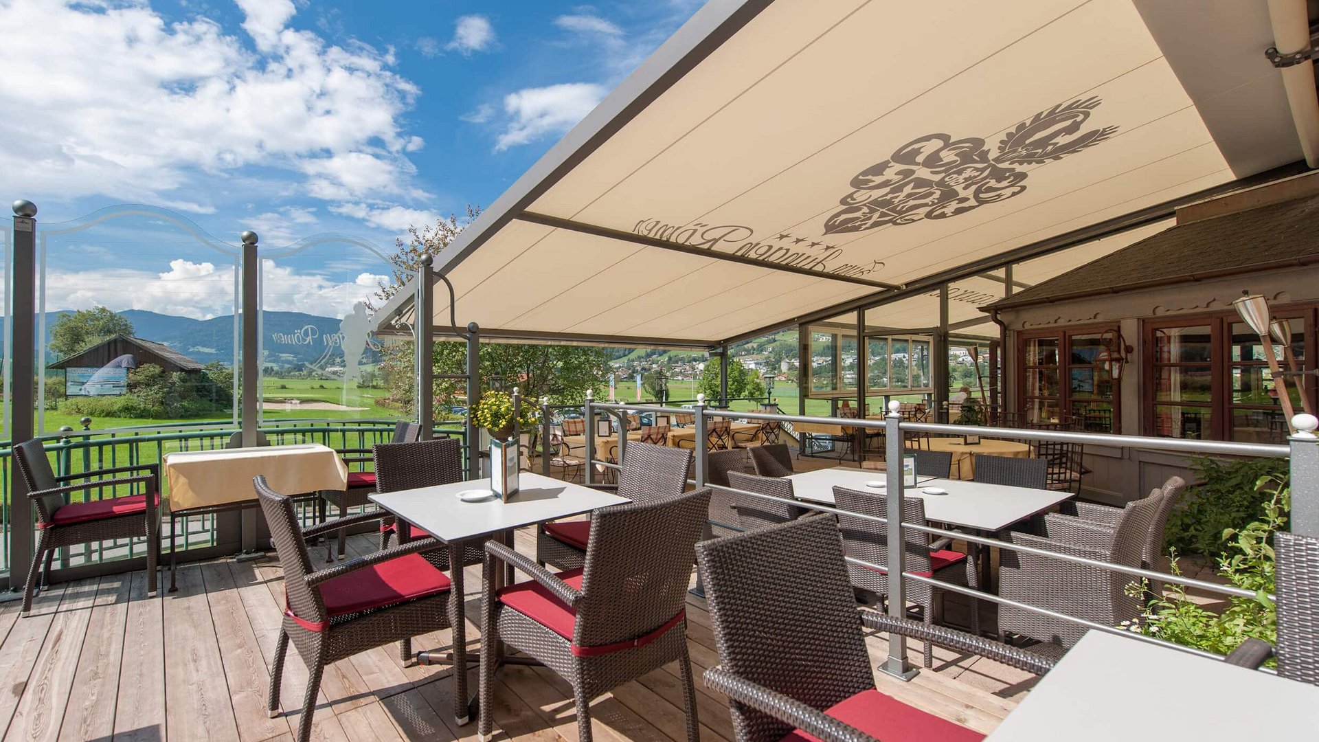 Outdoor terrace with tables and chairs overlooking mountains on a sunny day