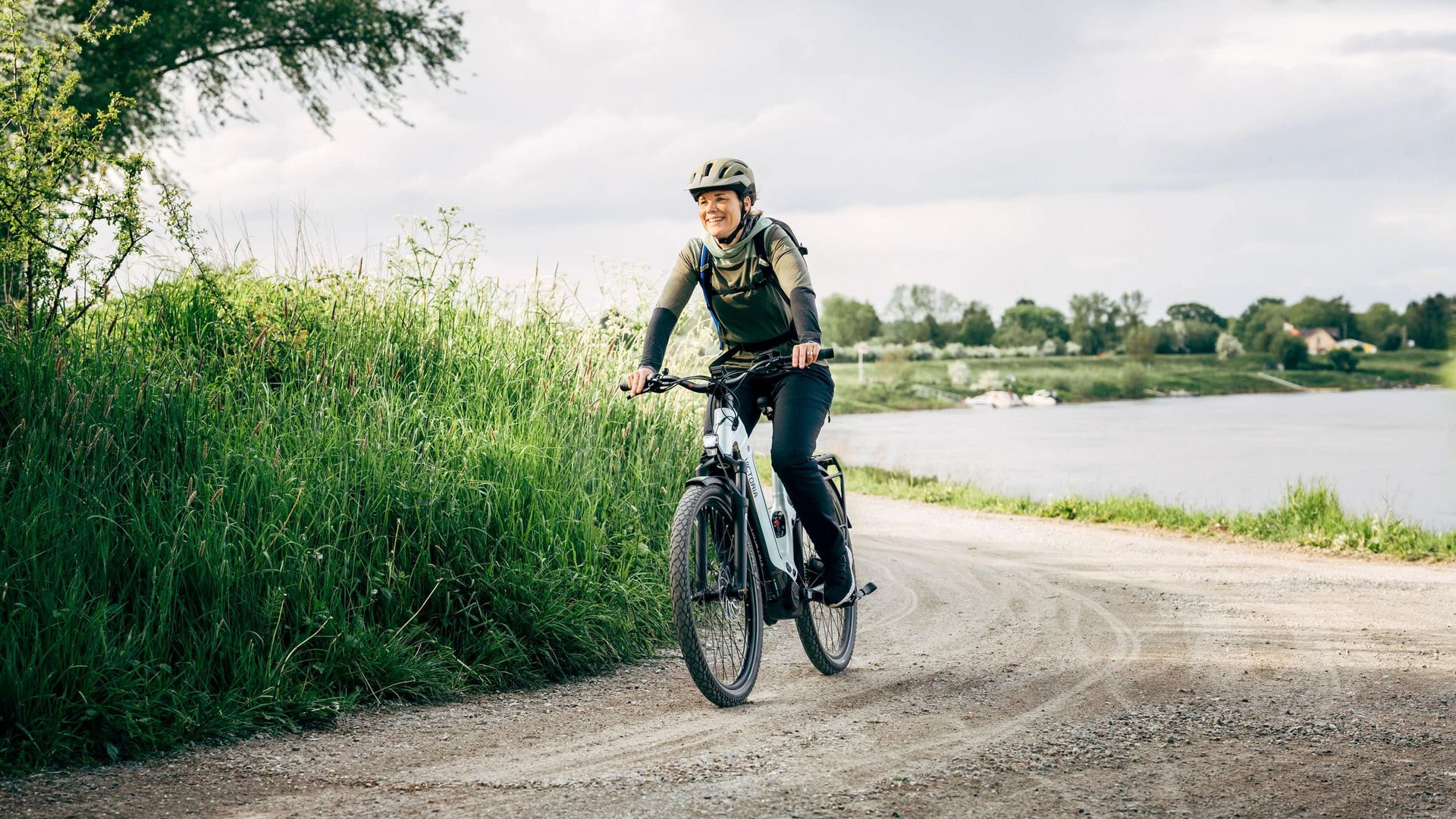 Victoria Woman smiling while riding a bike on a dirt road near a lake