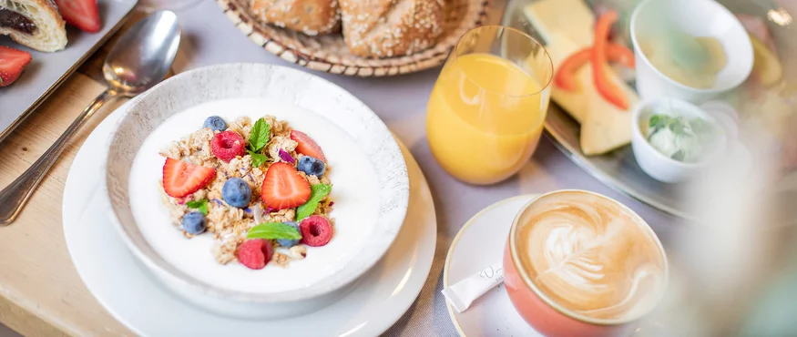 Breakfast with muesli, fresh berries, bread rolls, juice and coffee