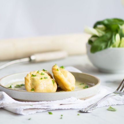 Two stuffed dumplings with sauce on a plate
