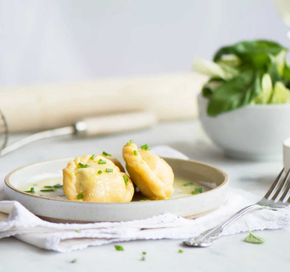 Twee gevulde deegkussentjes met saus op een bord