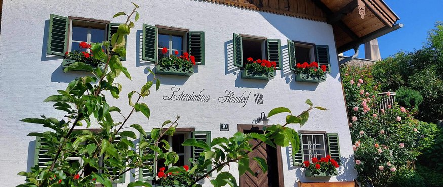 Zuckmayer Route © Literaturhaus Henndorf Wit huis met groene luiken en rode bloemen in bloembakken