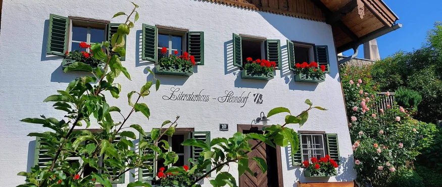 Wit huis met groene luiken en rode bloemen in bloembakken