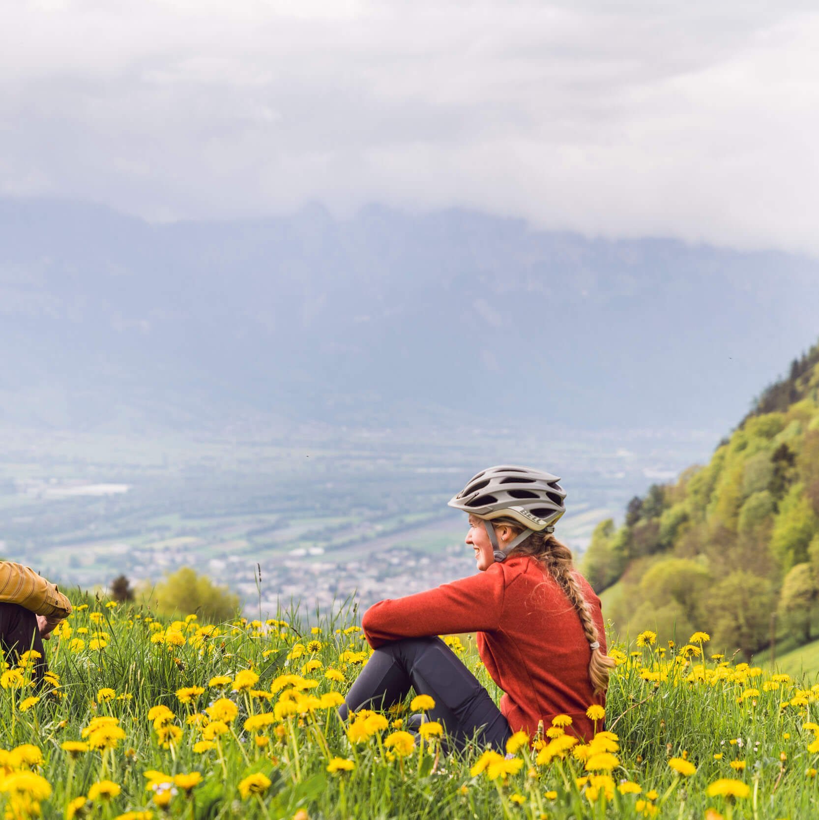 Zwei Radfahrer sitzen im Blumengarten in den Bergen und genießen die Aussicht