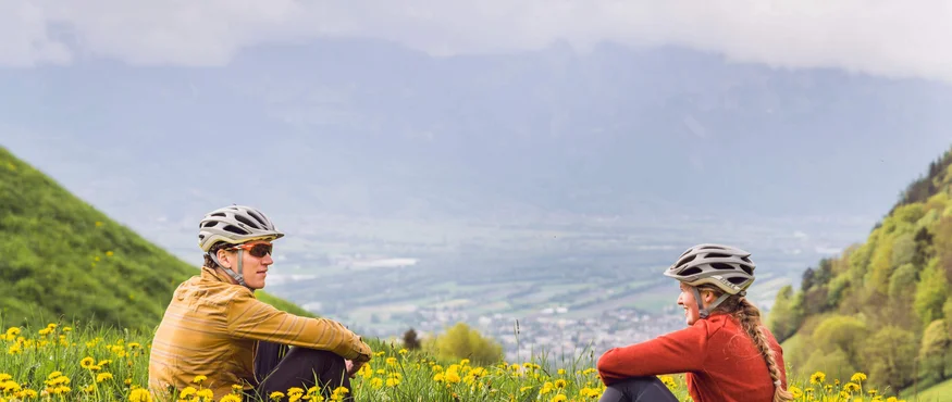 Zwei Radfahrer sitzen im Blumengarten in den Bergen und genießen die Aussicht