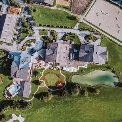 Luftaufnahme eines großen Gebäudekomplexes mit Teich und Gartenanlagen