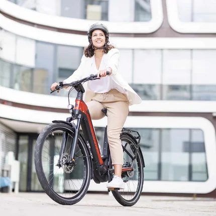 Frau fährt mit Helm ein modernes E-Bike in der Stadt