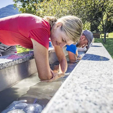 Mensen drinken water uit een buitensfontein