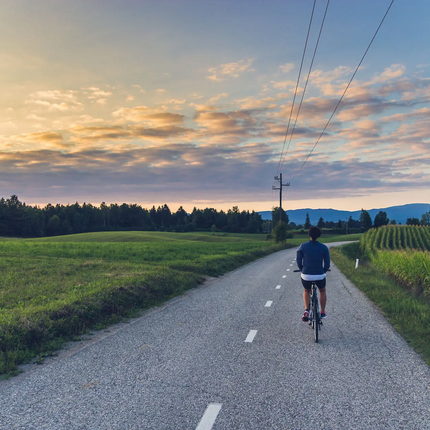 Person cycling on rural road at sunset