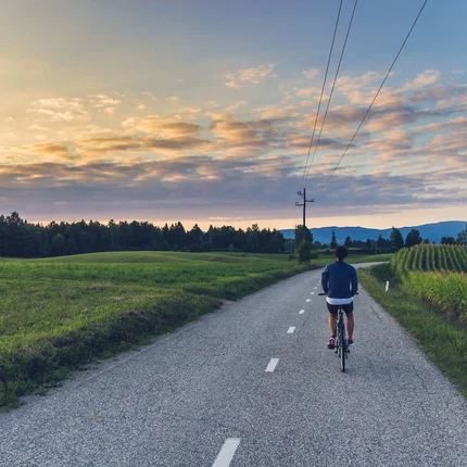 Persoon fietst op plattelandsweg bij zonsondergang