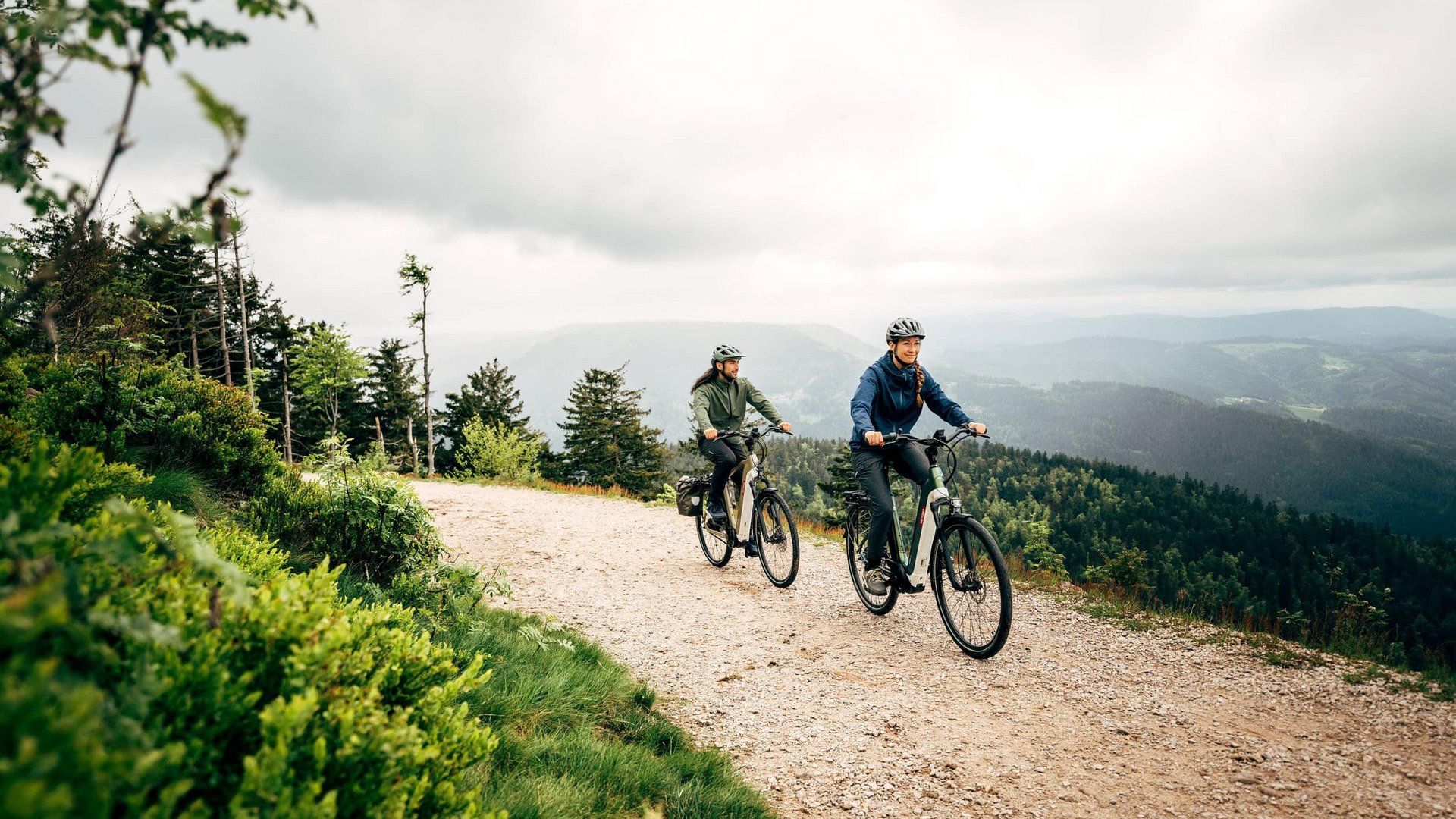 Victoria Two people cycling on a mountain trail under cloudy skies