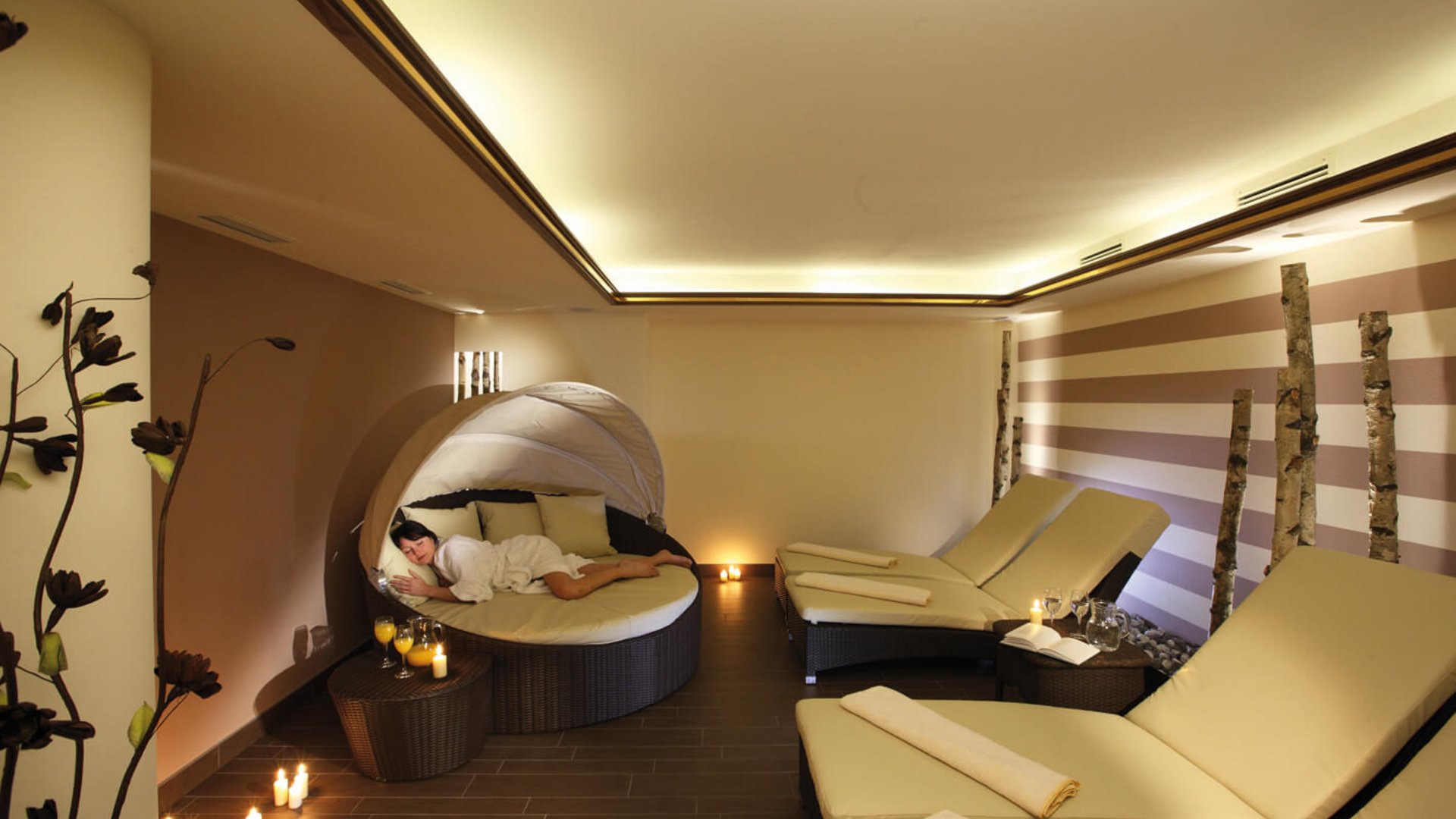 Woman relaxing in cozy lounge area with recliners and candlelight