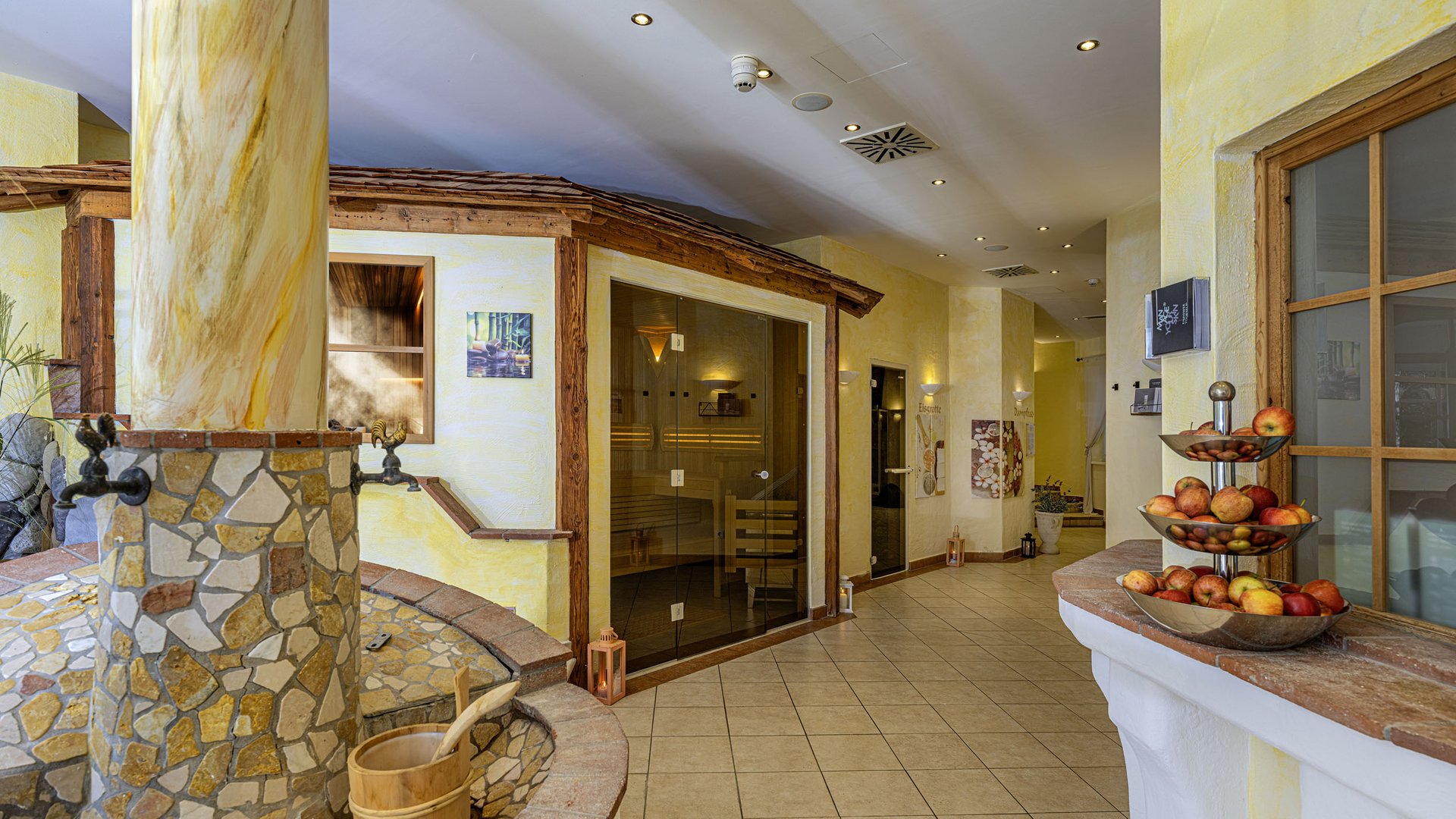 Indoor sauna area with stone fountain and bowl of apples