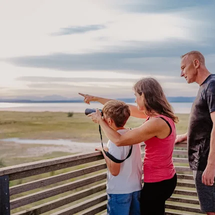 Familie beobachtet die Landschaft mit Fernglas auf einem Aussichtspunkt