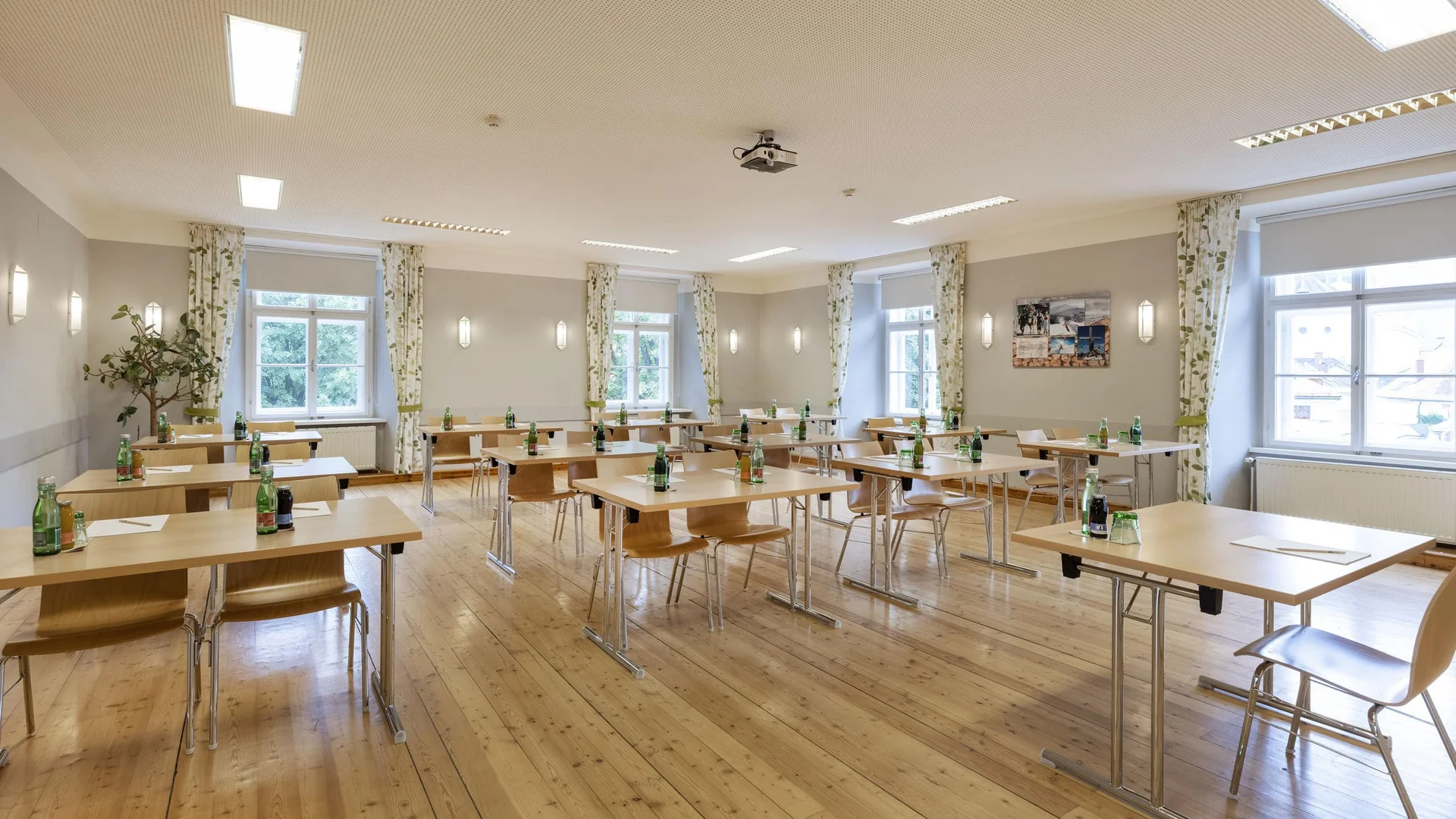 Bright seminar room with individual tables, chairs and water bottles