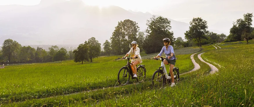 Twee vrouwen fietsen op een grasachtig pad bij zonnig weer